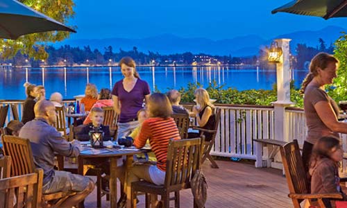 family at restaurant on lake waterfront with mountains silhouette in the distance
